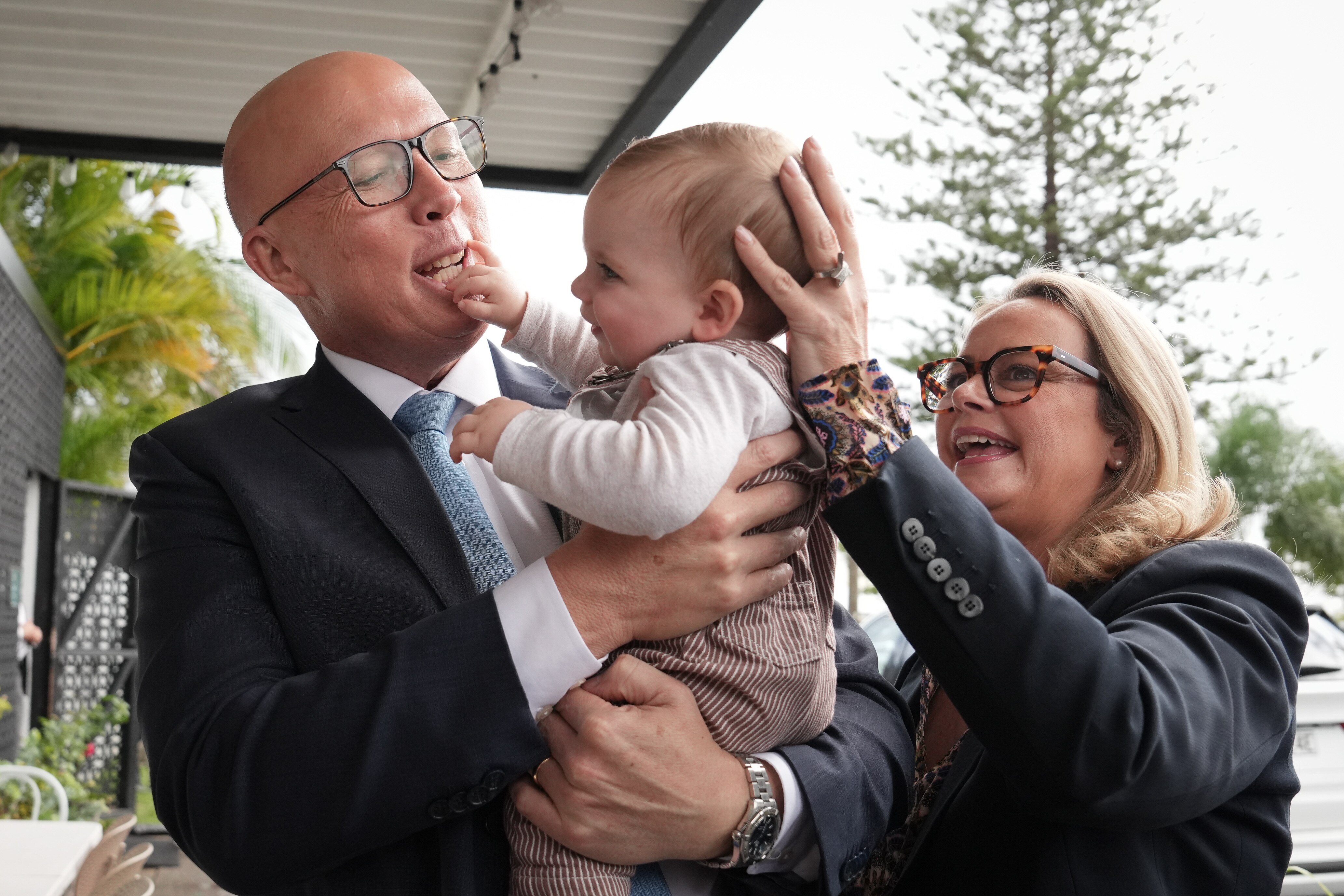 Dutton holds baby who is stiking its hand in Dutton&#x27;s mouth