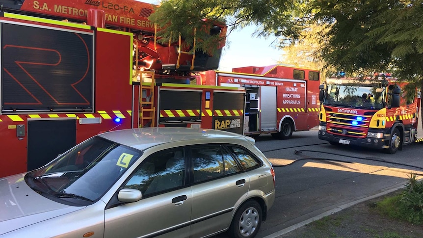 Three fire trucks and a car in a narrow street