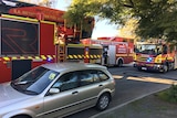 Three fire trucks and a car in a narrow street