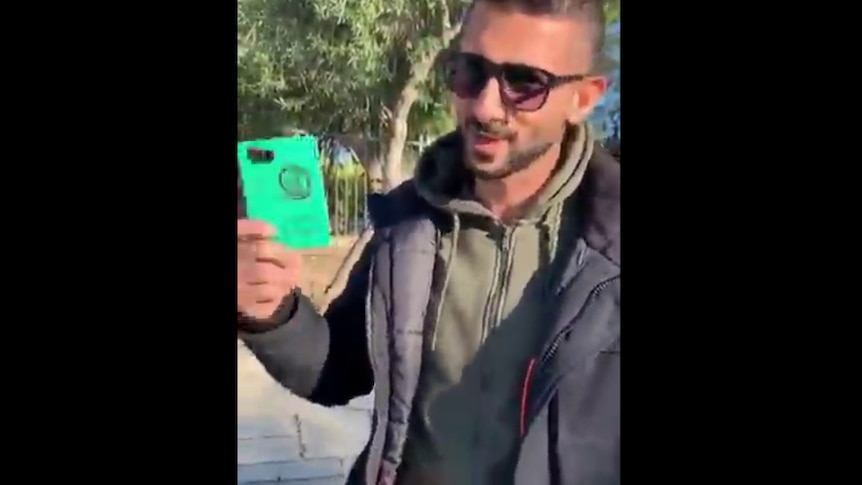 Man in sunglasses holds up Vanuatu passport.