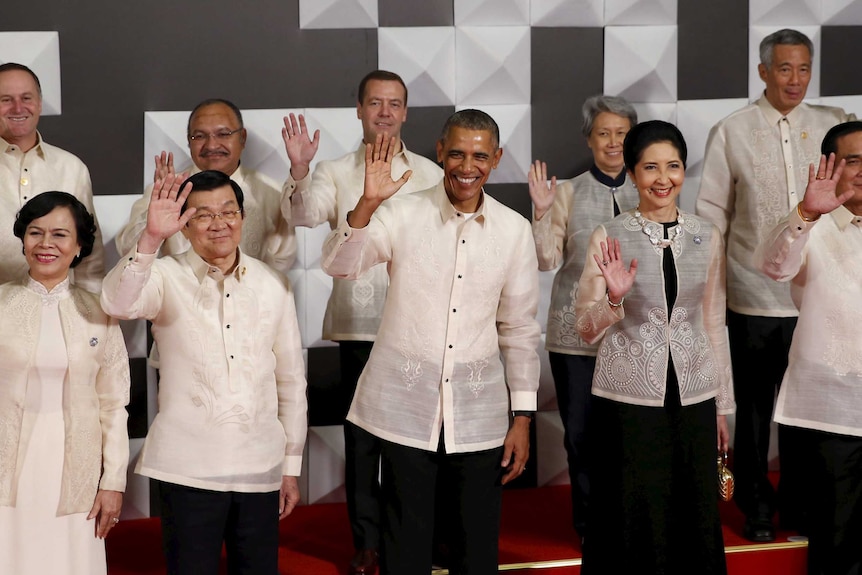 Leaders wave together in traditional dress at apec summit
