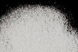 A white, crystalline powder spread on a dark background.