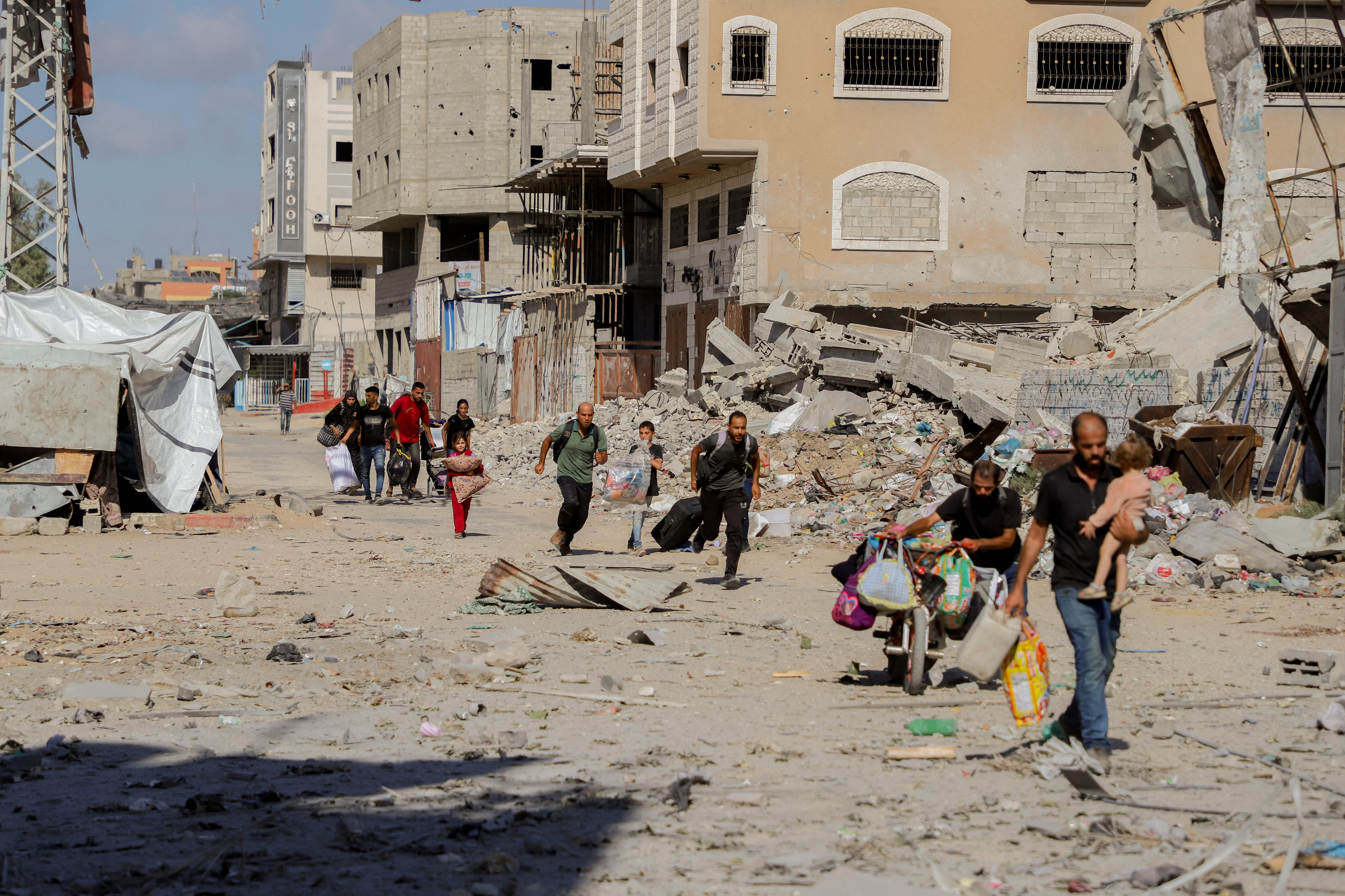 A trail of people walk through a desolate landscape.