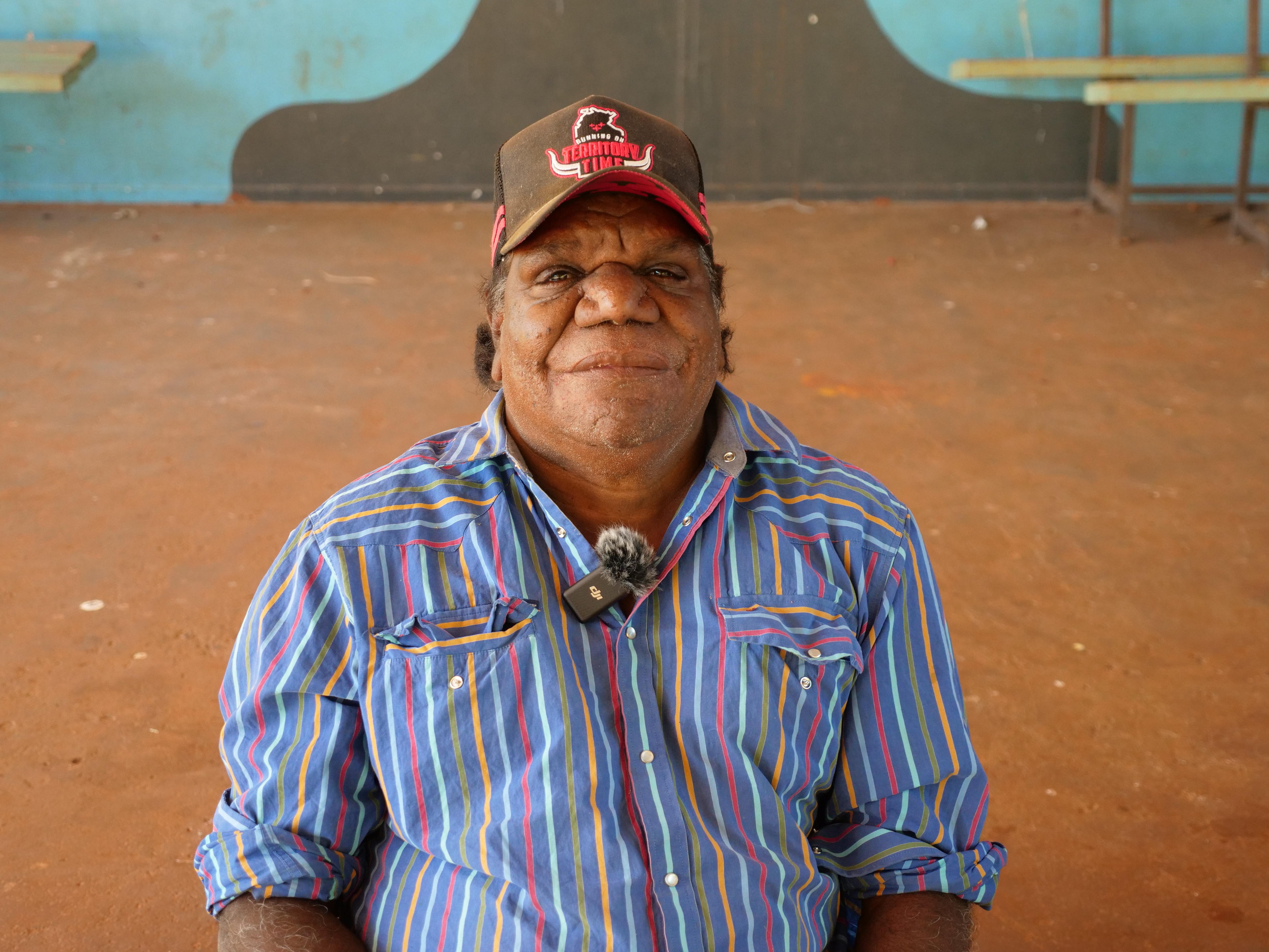 an aboriginal man wearing a cap and stripey shirt
