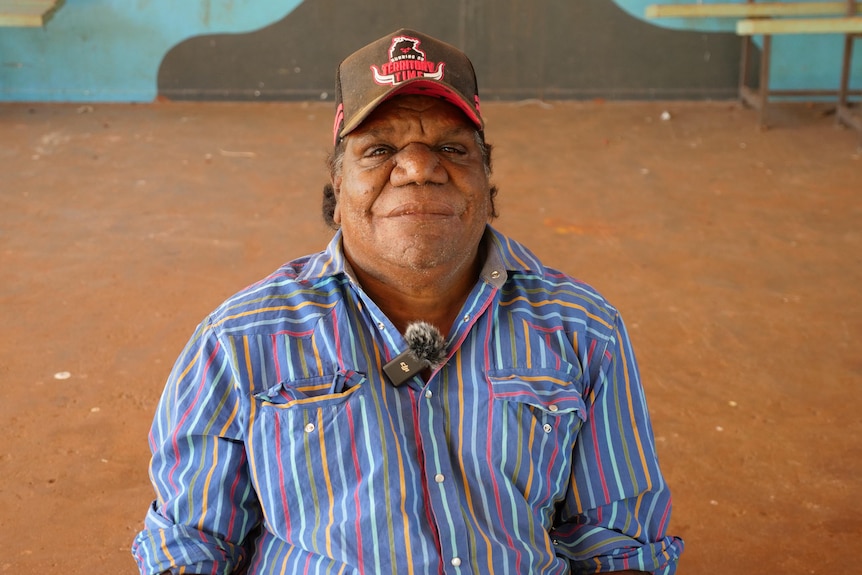 an aboriginal man wearing a cap and stripey shirt