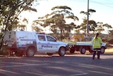 A woman stands in front of a road closed sign at the scene of a multiple fatal crash scene in the Goldfields.