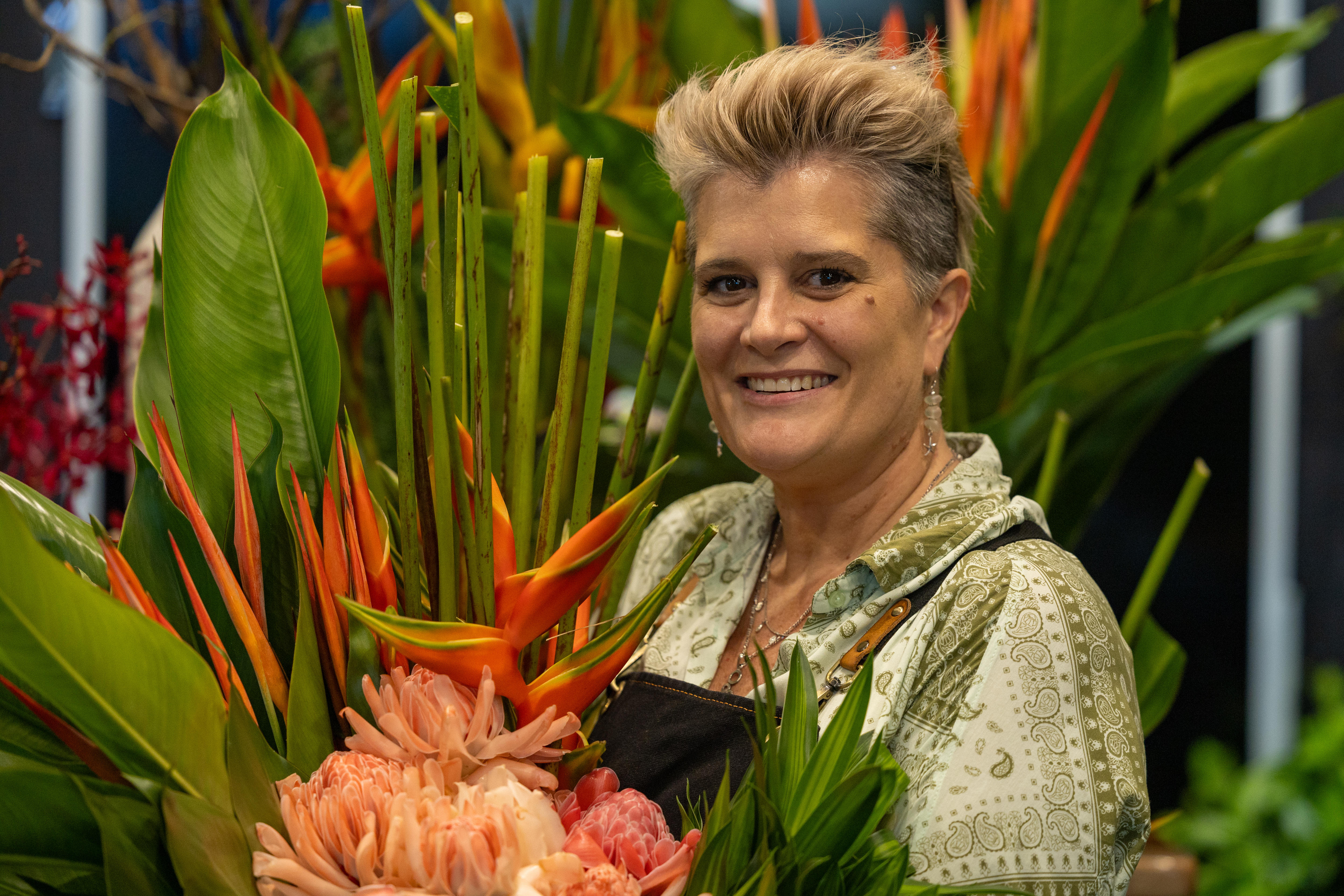A woman stand amougst an abundance of tropical flowers 