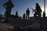 Afghan security forces stand over a body of a Taliban militant