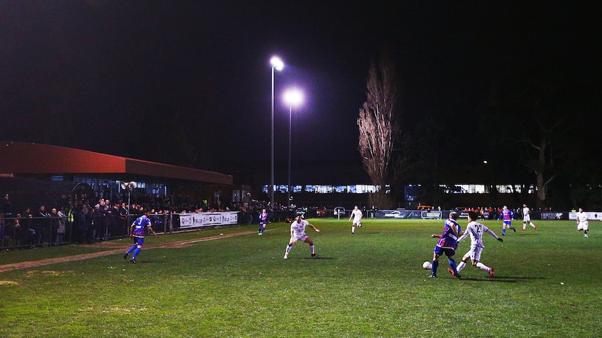 Male soccer players during a match at night under lights