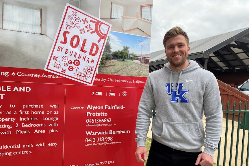 a man infront of a sold sign