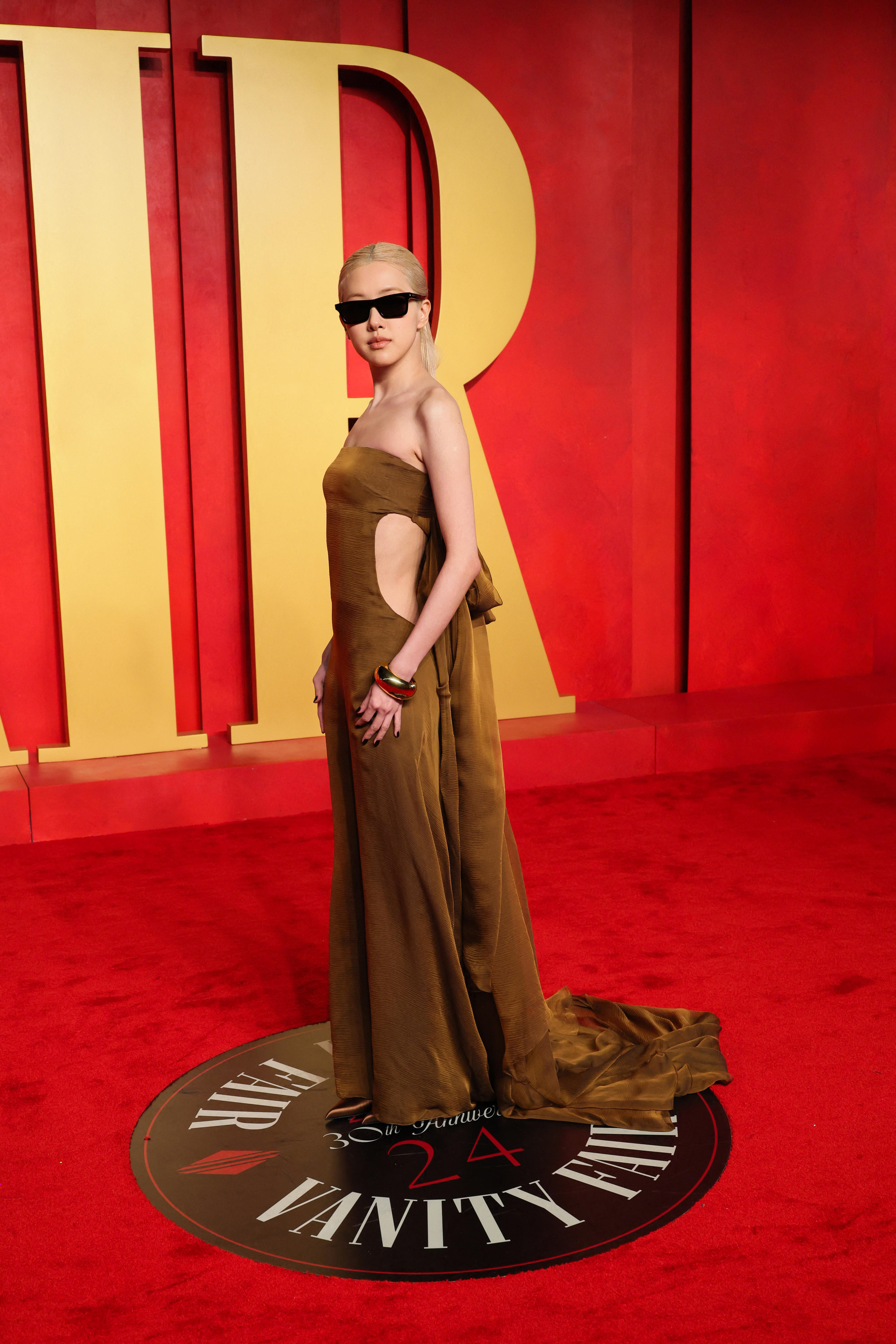 Rose wearing a mustard gold strapless gown with a cutout sides and a pair of black sunglasses