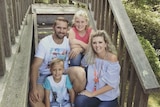Angela, Brenden and their two children sit smiling on the steps
