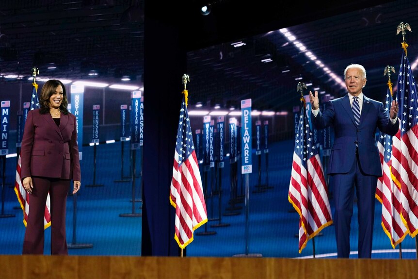 Joe Biden and Kamala Harris stand on a stage in front of several US flags