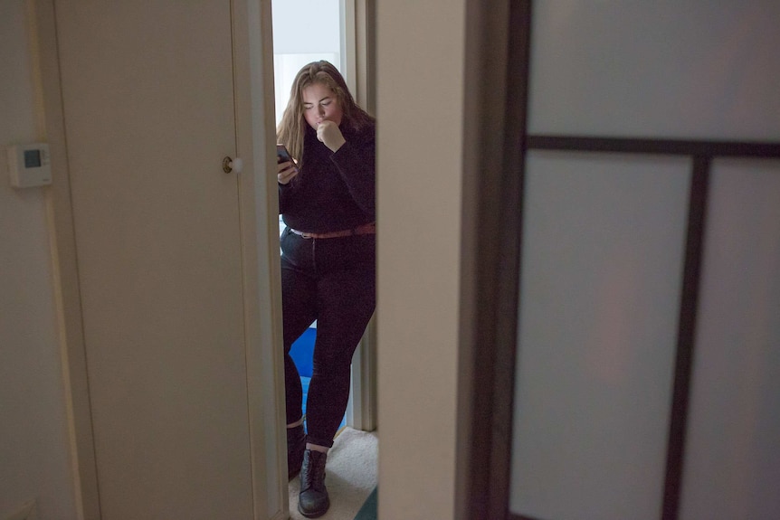 Molly Willmott checks social media on her phone while brushing her teeth.