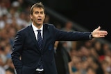 Julen Lopetegui, stands with a stunned expression on his face with one arm out stretched with a crowd on bleechers behind him