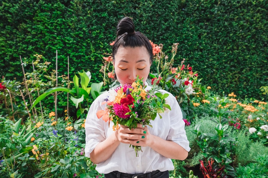 woman in a garden smelling a bunch of flowers