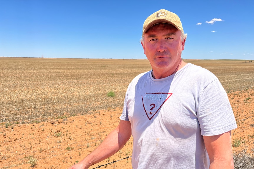 Andrew Willsmore is standing in front of a dry farm paddock