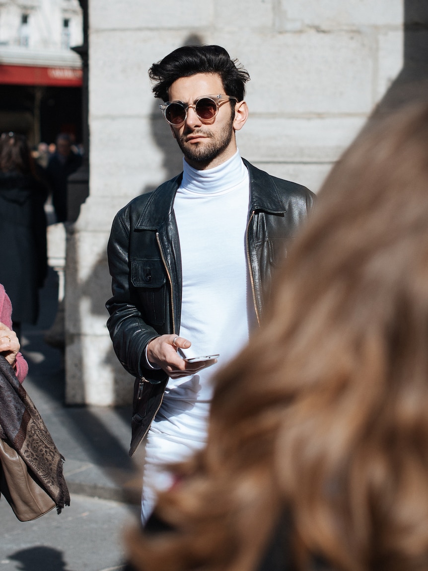 A man in Paris wears a  white turtleneck and black leather jacket.