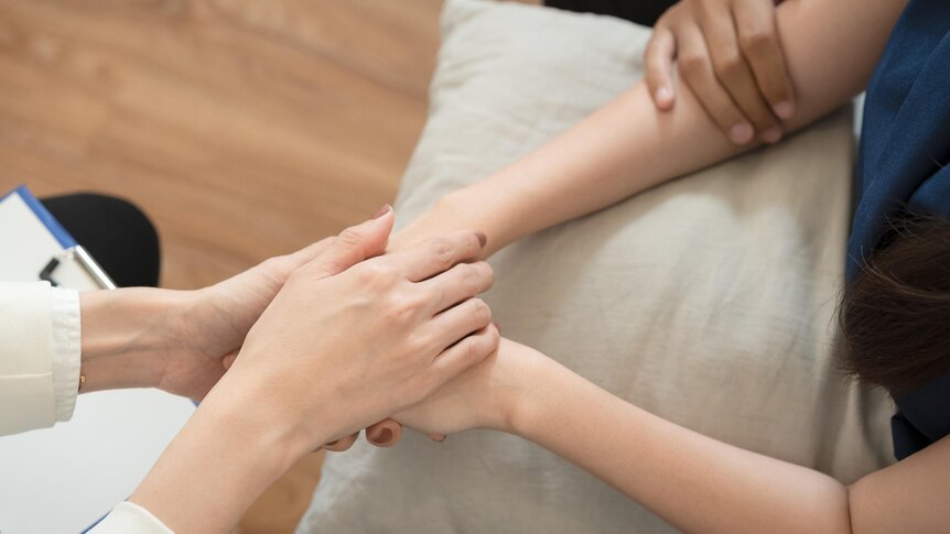 Two people holding hands over a pillow