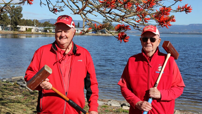 Charlie Martin and Arthur Felvus stand by Lake Illawarra with their croquet mallets in hand.