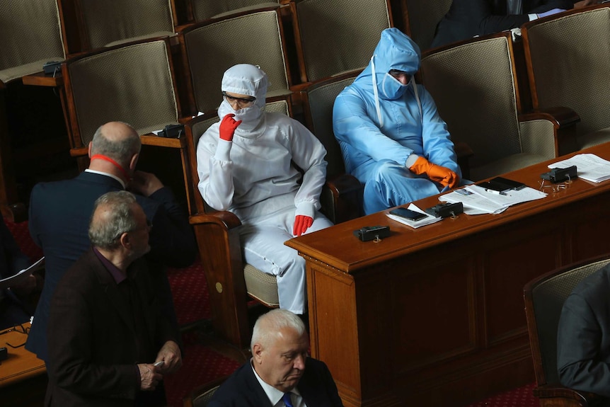 Two people in full hazmat gear sitting in Bulgaria's parliament