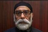 Gurpatwant Singh Pannun, pictured in front of a dark wooded background, looks at the camera.