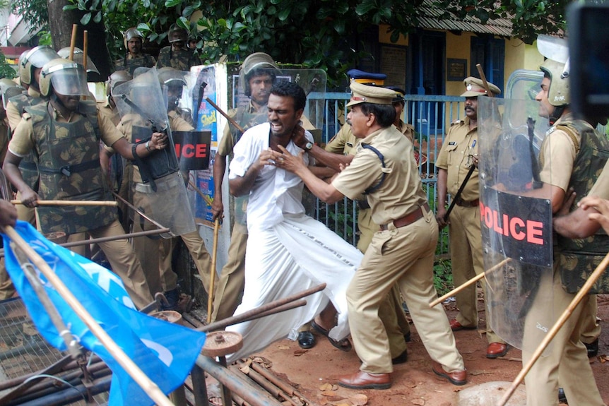 Police hold shields and scuffle with a protester.