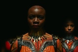 Two black woman dressed for battle, one with head shaved