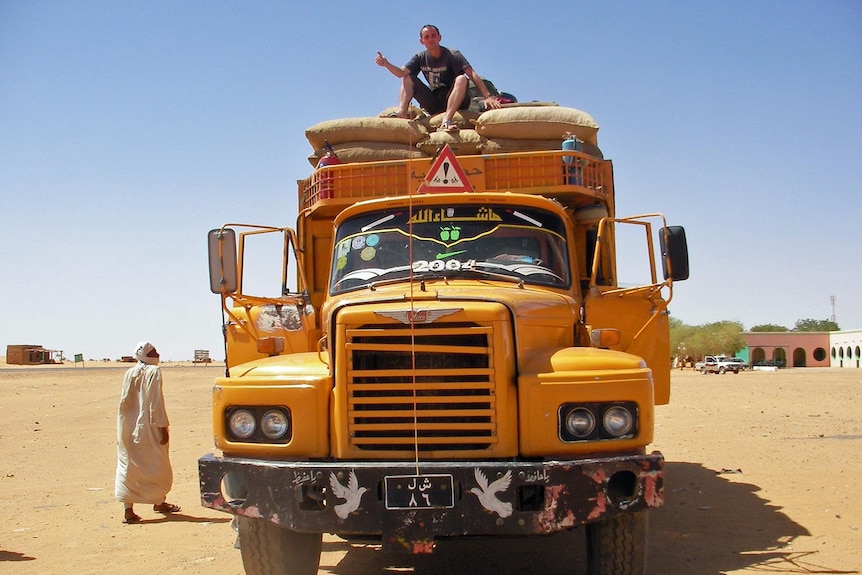 Jeremy hitches a ride on a truck in Sudan.