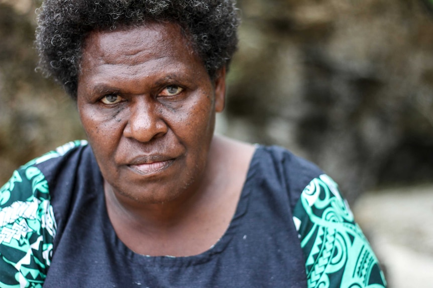 A woman from the island of Tanna in Vanuatu poses for a portrait with a serious expression on her face.