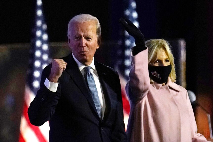 Joe Biden raises his fist while Jill Biden waves