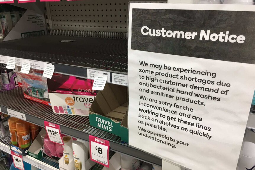 A sign in front of empty shelves at a supermarket