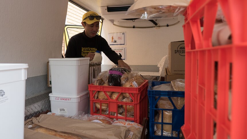 Oz Harvest volunteer driver Justin Yee prepares food for delivery.