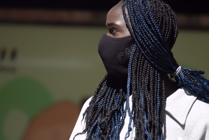 A close-up picture of a woman with braided hair wearing a face mask.