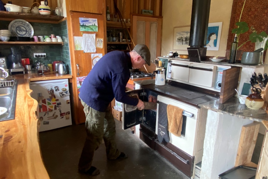 A man putting firewood into an oven 