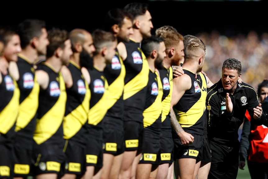 Damien Hardwick claps his players in encouragement after the conclusion of the national anthem