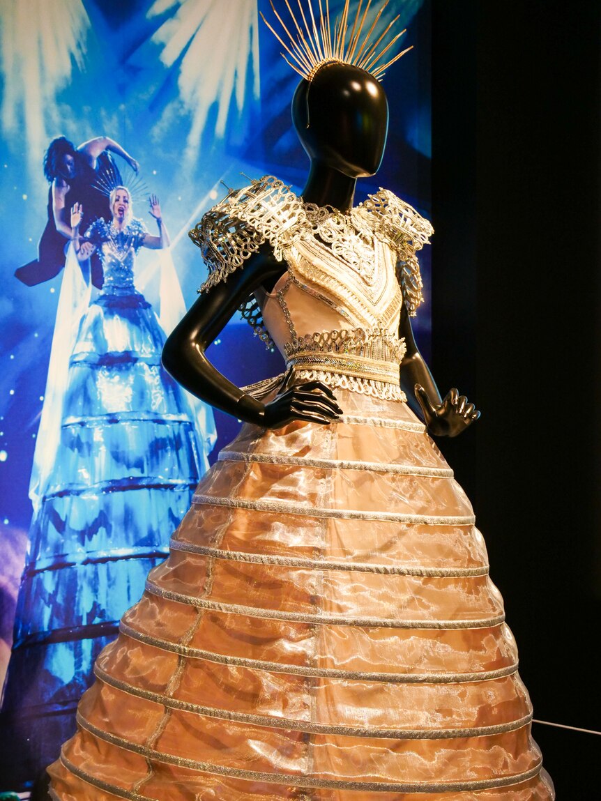 White costume on a mannequin in front of a photo.