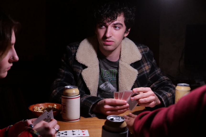 A young man holding playing cards.