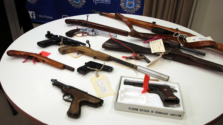 A range of different types of firearms spread out on a table.