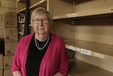 Sue Jordan stands next to empty shelves.