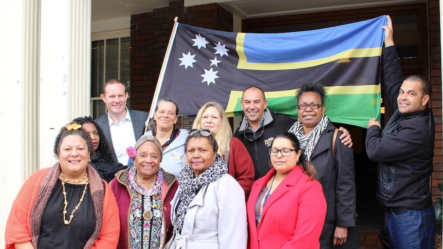 A group of South Sea Islanders stand in front of their flag at the Petersham Town Hall in inner west Sydney