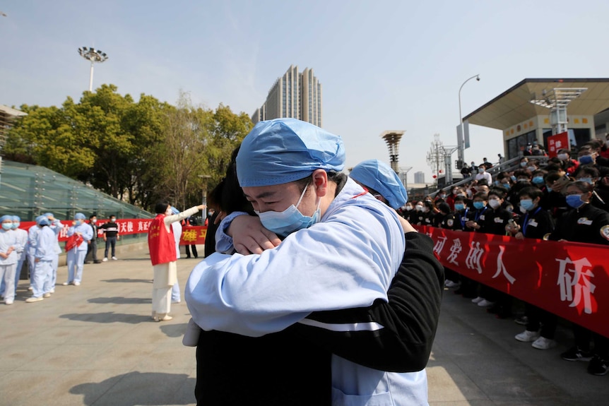 An emotional medical worker embraces another medical worker as they bid farewell in Wuhan.