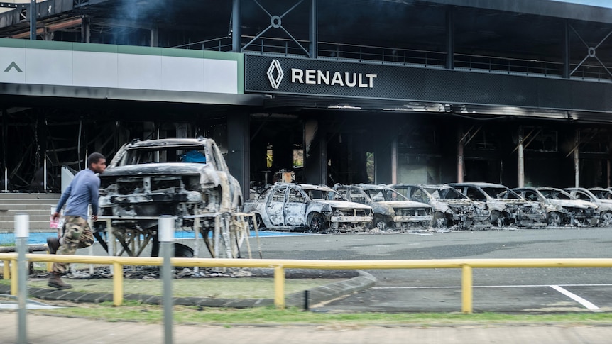 This photograph shows a view of burnt cars and a burnt Renault car shop amid protests in New Caledonia.