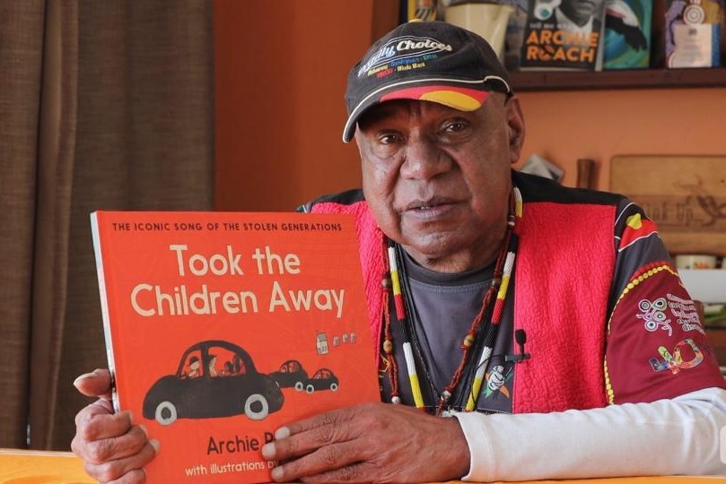 Archie Roach holds book with title "Took the Children Away"