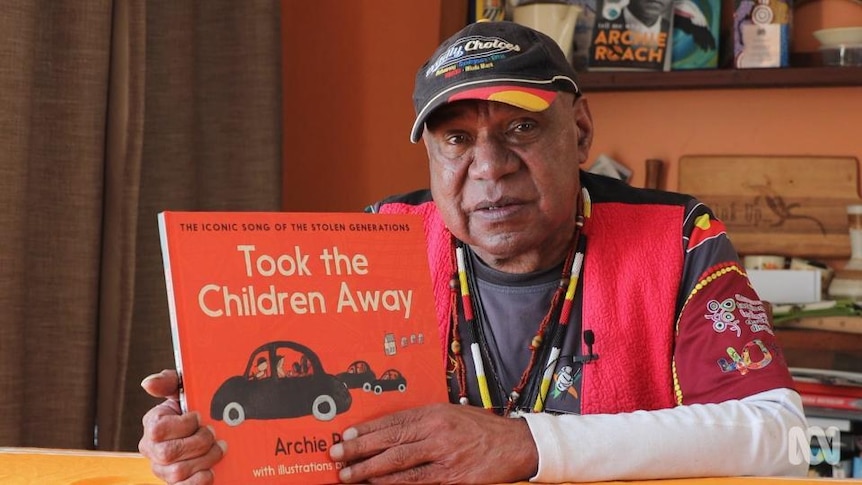 Archie Roach holds book with title "Took the Children Away"