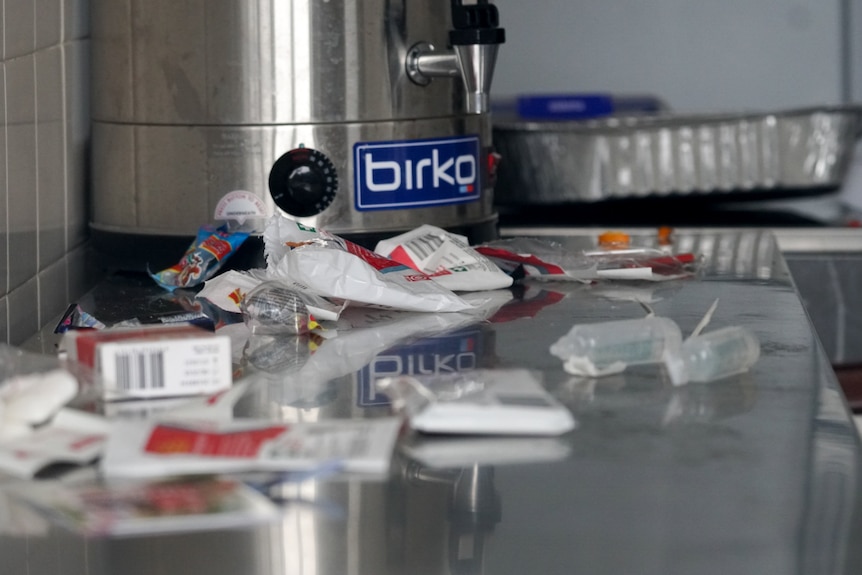 Packaging from medical supplies strewn on a bench in the hall kitchen.