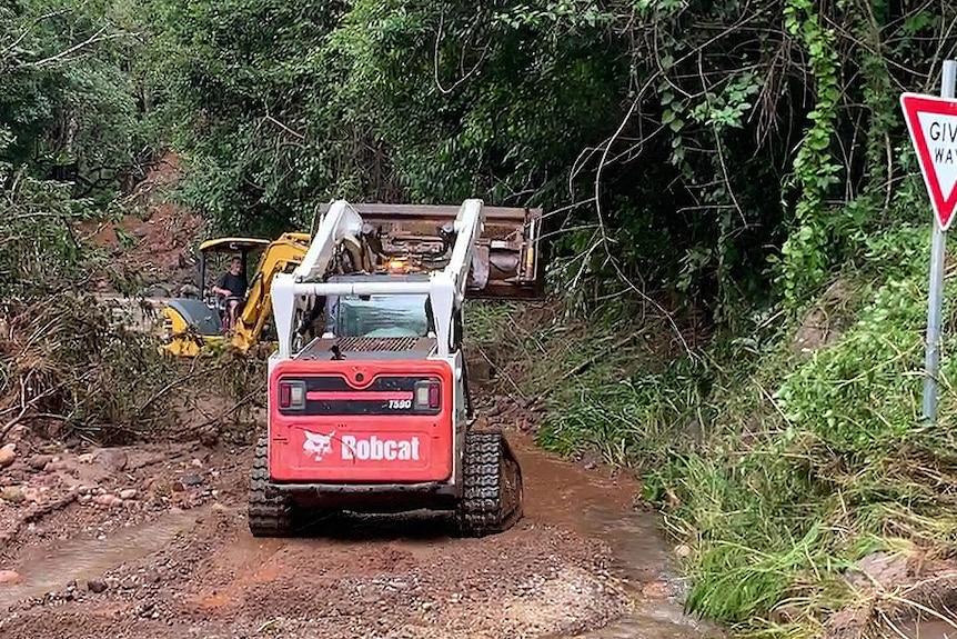 Two earthmoving machines clear dirt