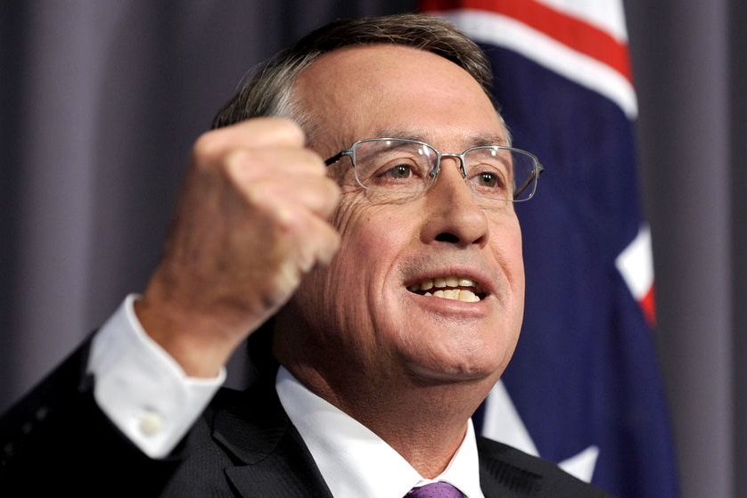 A mad shaking his fist in front of the Australian flag.