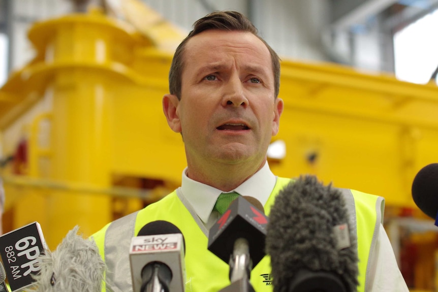 A head and shoulder sshot of Mark McGowan talking into microphones.