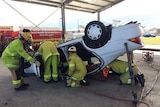 Emergency crew does exercise using Jaws of Life equipment to rescue person trapped in overturned car in Brisbane